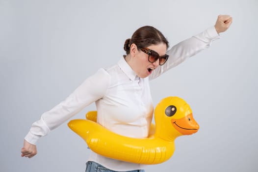 Excited woman in white shirt dreaming about vacation, wearing sunglasses and inflatable duck