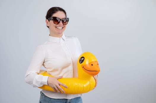 Caucasian woman in a white shirt dreaming of a vacation and wearing sunglasses and an inflatable duck