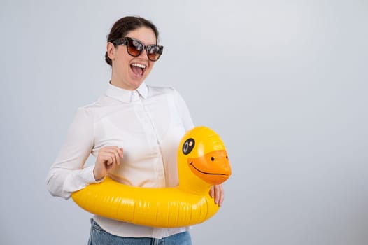 Caucasian woman in a white shirt dreaming of a vacation and wearing sunglasses and an inflatable duck