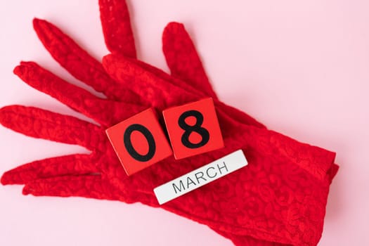 Beautiful red lace gloves on which are wooden cubes with the inscription March 8. Ready card for the holiday, Women's Day