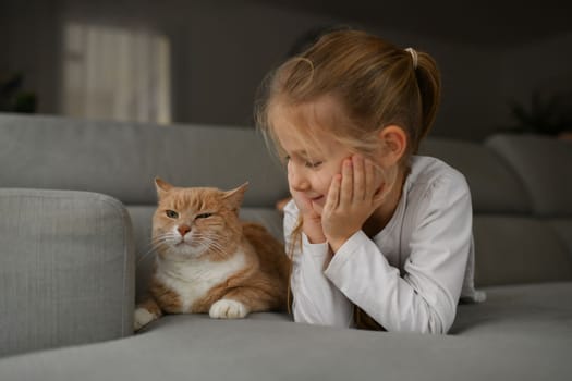 A girl near a ginger cat on the sofa