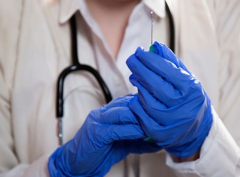 The doctor's hands spray medicine and liquid from the needle. Close-up. The concept of vaccination, injection, injections.