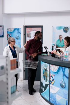 Adult customer putting pharmaceutics products on counter, preparing to pay for treatment. African american client taking boxes of drugs and supplements from drugstore, medicine service