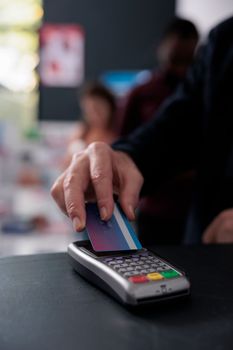 Senior customer putting credit card on pos terminal paying for health care treatment in drugstore, buying vitamins, supplements to help cure disease. Medicine support service. Close up