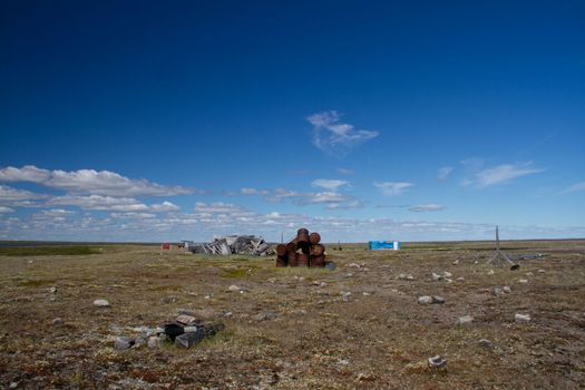 Abandoned camp with fuel barrels and buildings on a bare arctic summer landscape. Near Arviat, Nunavut, Canada