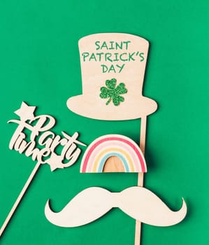 Flat lay with hat, clover, rainbow on wooden table with St. Patrick's day lettering