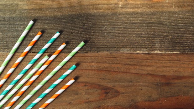 Multicolored straws for St. Patrick's Day for cocktails on a rustic wooden background with copy space