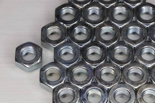 Threaded metal hex nuts neatly sorted on white surface