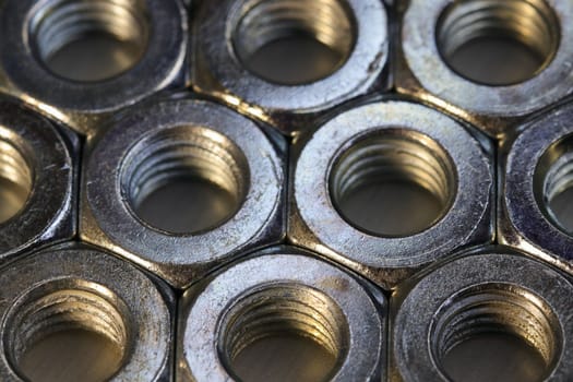 Organized threaded metal hex nuts close-up on flat surface