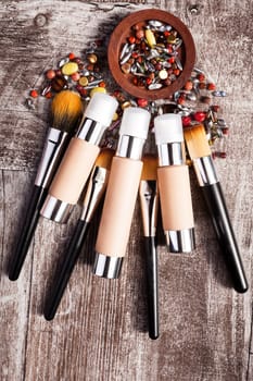 Cosmetics products and brushes in conceptual image over wooden background. Beauty accessories. Professional products