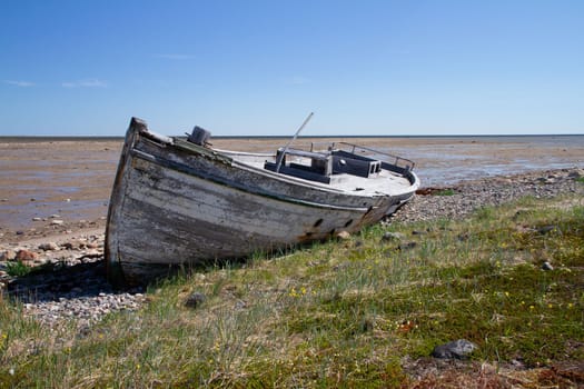 Front view of old wooden boat wrecked and stranded on a rocky shoreline, north of Arviat, Nunavut, Canada