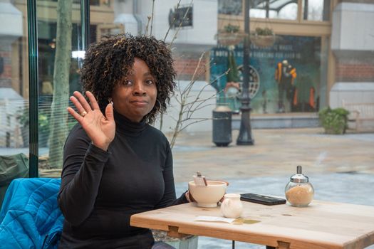 African american young woman without makeup sits in a cafe in the morning, having just woken up, and drinks coffee, High quality photo