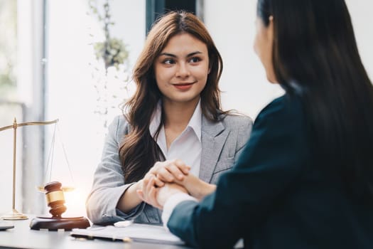 Lawyers holding business woman hand while consult at lawyer office. Law, legal services, advice, Justice and real estate concept.