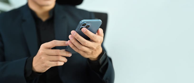 Cropped image of businessman in black suit using smart phone. Copy space for your advertise text.