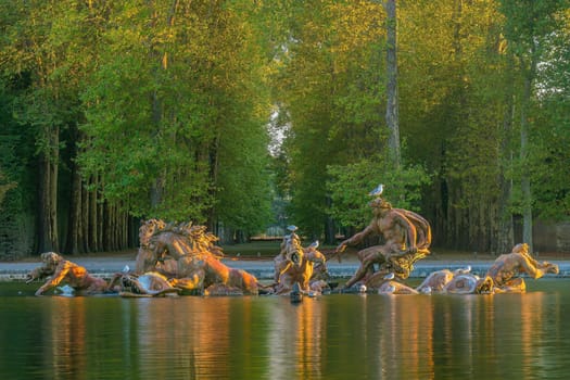 Garden of Chateau de Versailles and Apollo's fountain, near Paris in France at sunset