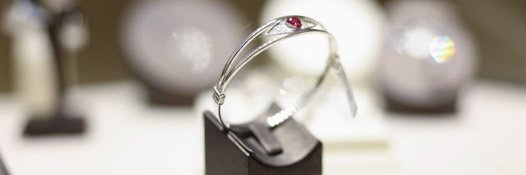 White gold ring with ruby on shop window closeup. Sale of jewelry closeup