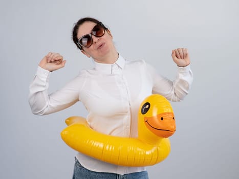 Caucasian woman in a white shirt dreaming of a vacation and wearing sunglasses and an inflatable duck