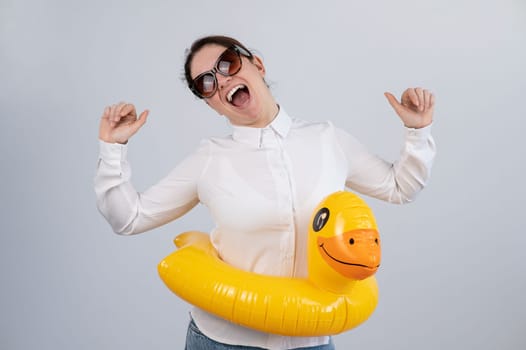 Caucasian woman in a white shirt dreaming of a vacation and wearing sunglasses and an inflatable duck