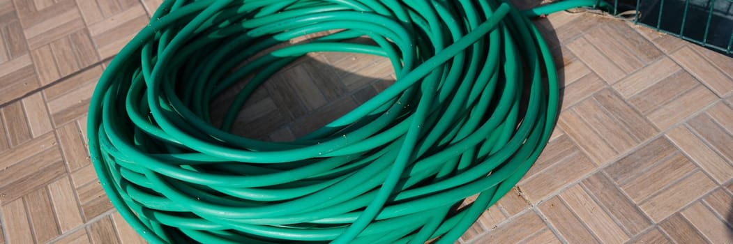 Green twisted garden hose in garden. Watering system and choosing a quality garden hose