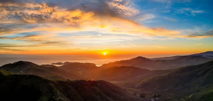 Sunset over ocean with rugged mountain coast and beautiful color in clouds. High quality photo