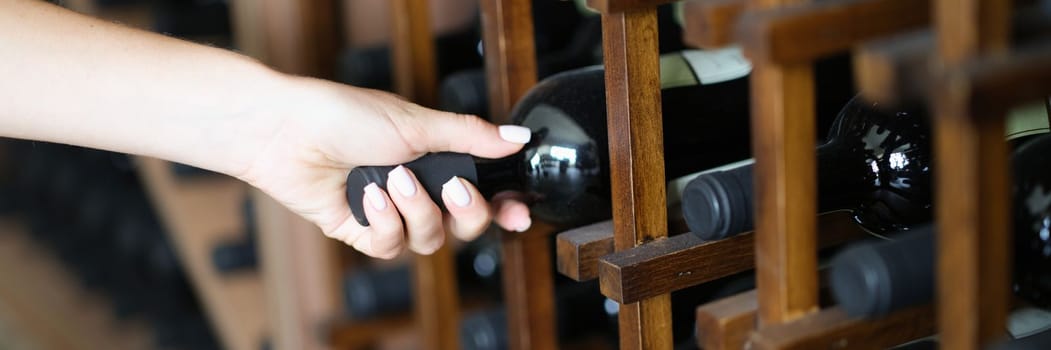 Bartender taking bottle of wine from shelf in basement. Wine tasting from wine tasting club concept