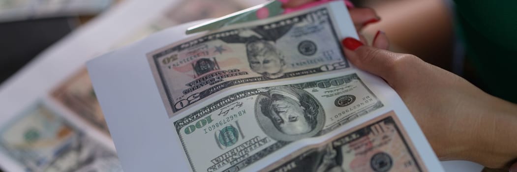 Counterfeiter cuts dollar bills with scissors closeup. Concept of counterfeit money printed on printer