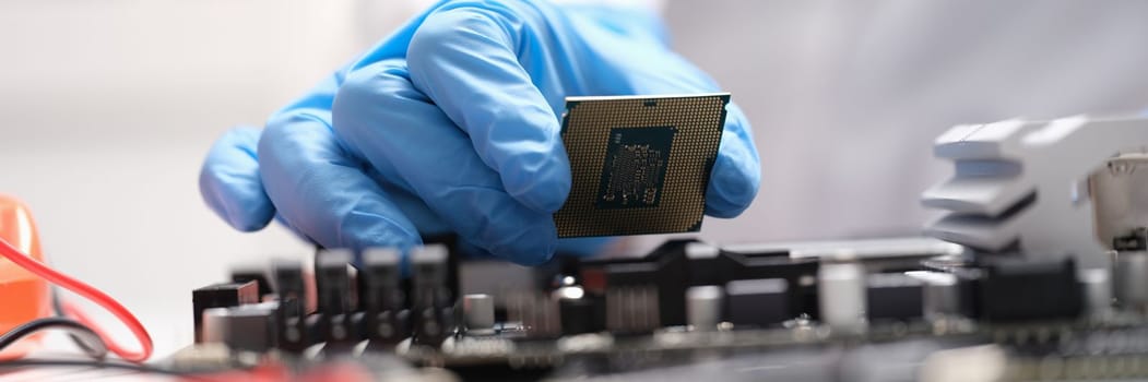 Technician connects a CPU microprocessor to motherboard socket. Repair and maintenance of computer equipment concept