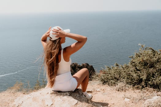 Woman travel sea. Young Happy woman in a long red dress posing on a beach near the sea on background of volcanic rocks, like in Iceland, sharing travel adventure journey