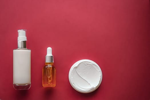 Skincare cosmetics and anti-aging beauty products, luxury skin care bottles, oil, serum and face cream on coral background.