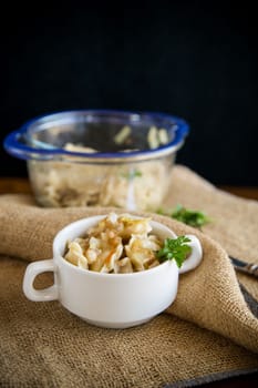 cooked dumplings with potatoes and fried onions, in a bowl on a wooden table.