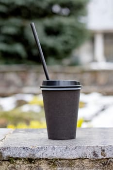 Paper cup with coffee on a concrete bench in park