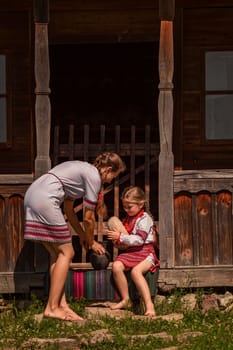 mother and daughter in Ukrainian folk dresses on the threshold of the house.