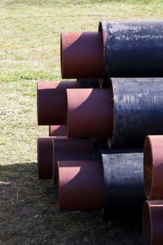 Black metal pipes for water pipes folded on the grass close up, copy space