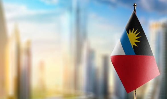 Small flags of the Antigua and Barbuda on an abstract blurry background.