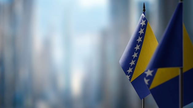 Small flags of the Bosnia and Herzegovina on an abstract blurry background.