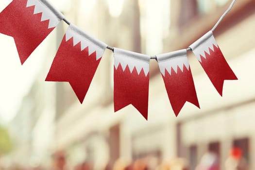 A garland of Bahrain national flags on an abstract blurred background.