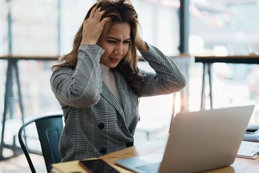 Portrait of business owner, woman using computer and financial statements Anxious expression on expanding the market to increase the ability to invest in business.