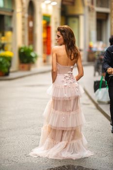 A bride in a pink wedding dress walks in Florence, Italy.