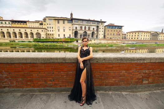 Beautiful stylish bride in a black dress stands on the embankment in Florence, Italy.