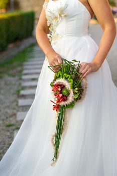 an unusual elongated wedding bouquet in the hands of the bride.