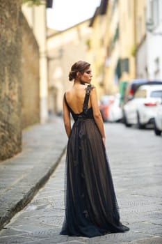 A beautiful stylish bride in a black dress walks through Florence, a Model in a black dress in the old city of Italy.