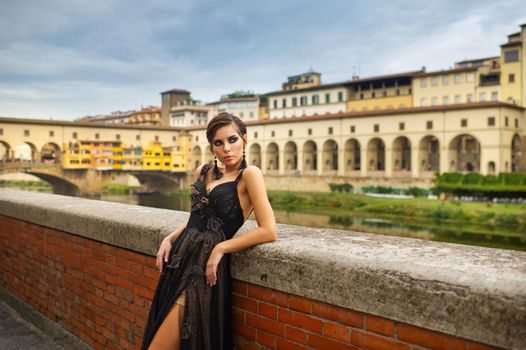 Beautiful stylish bride in a black dress stands on the embankment in Florence, Italy.