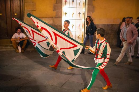 SIENA, Italy-October 13, 2018: Locals with flags walk through the streets in the center of Siena.