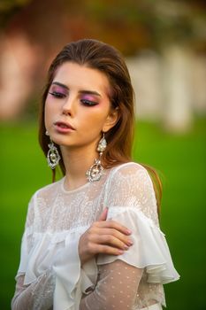 A bride in a white wedding dress in a park in an Austrian town with large trees at sunset.