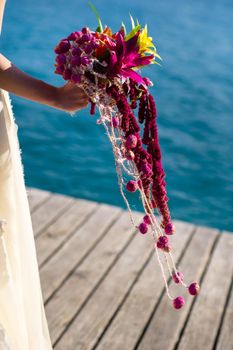 an unusual elongated wedding bouquet in the hands of the bride.