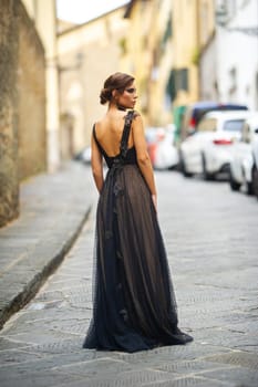 A beautiful stylish bride in a black dress walks through Florence, a Model in a black dress in the old city of Italy.