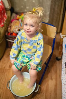 The girl caught a cold sits at home and is treated using hot water in a basin.