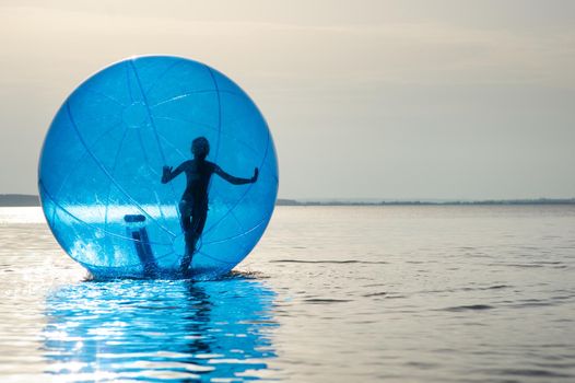 A girl in an inflatable attraction in the form of a ball on the sea.