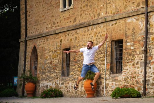 A man jumps near the Castle of Paschini, a medieval castle located in Castiglioncello in Tuscany. Italy, Livorno.
