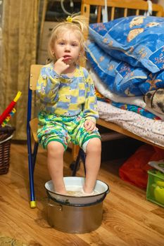 The girl caught a cold sits at home and is treated using hot water in a basin.